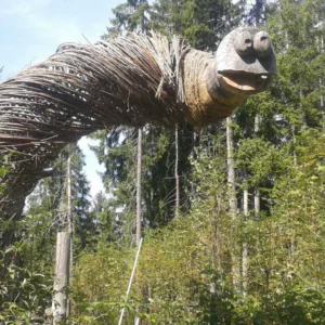 Beliggende i en skovs grønne omgivelser, har denne skulptur, der minder om de mytiske skabninger, man kunne forestille sig på en Sommerferie i Westendorf, vævede grene, der danner en stor slange med et udskåret træhoved, store øjne og en åben mund blandt høje træer.