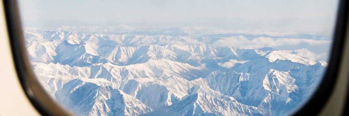 Transport til skiferien - udsigt over bjergkæde fra et flyvinduet