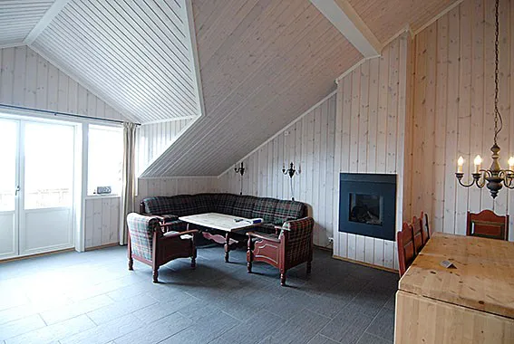 Et hyggeligt værelse i Westendorf med højt, skrå træloft og vægge er perfekt til din skiferie. Det har en plaid sofa, træbord med stole, moderne pejs og lysekrone. Naturligt lys oversvømmer rummet gennem et stort vindue og en glasdør.