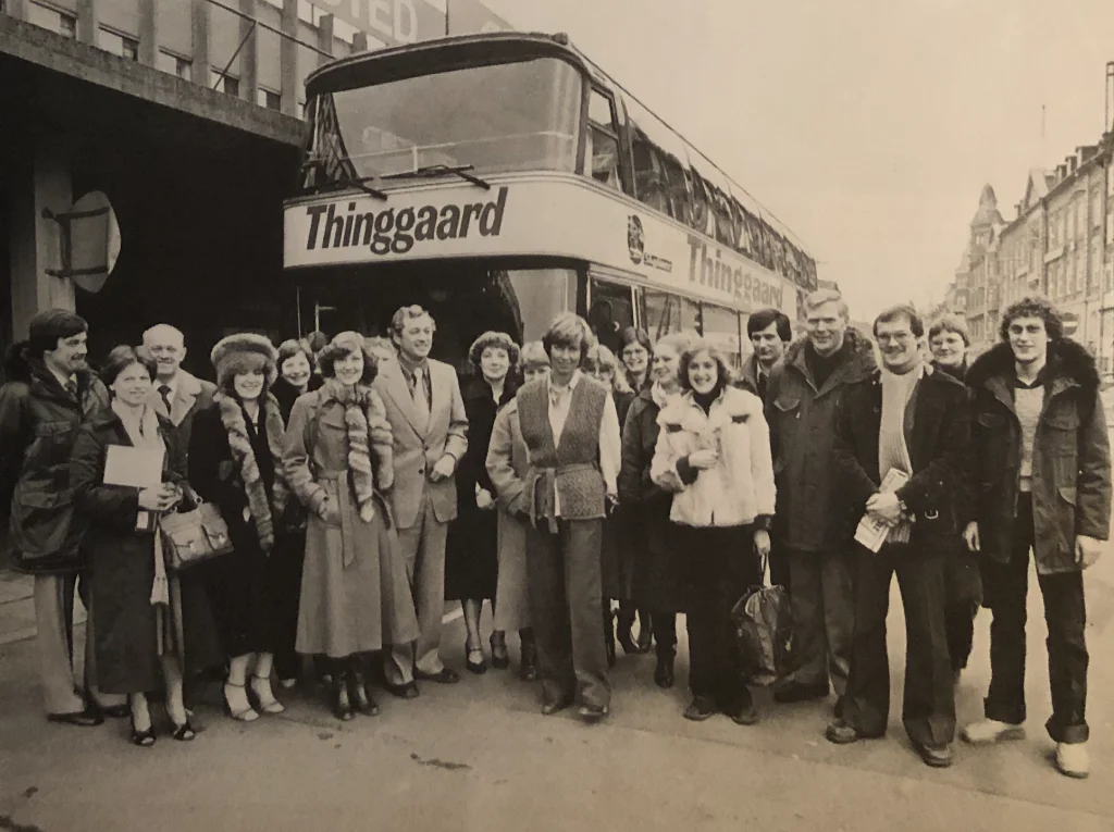 Billede af Thinggaard ansatte og rejseledere foran en dobbeltdækkerbus omkring 1980.